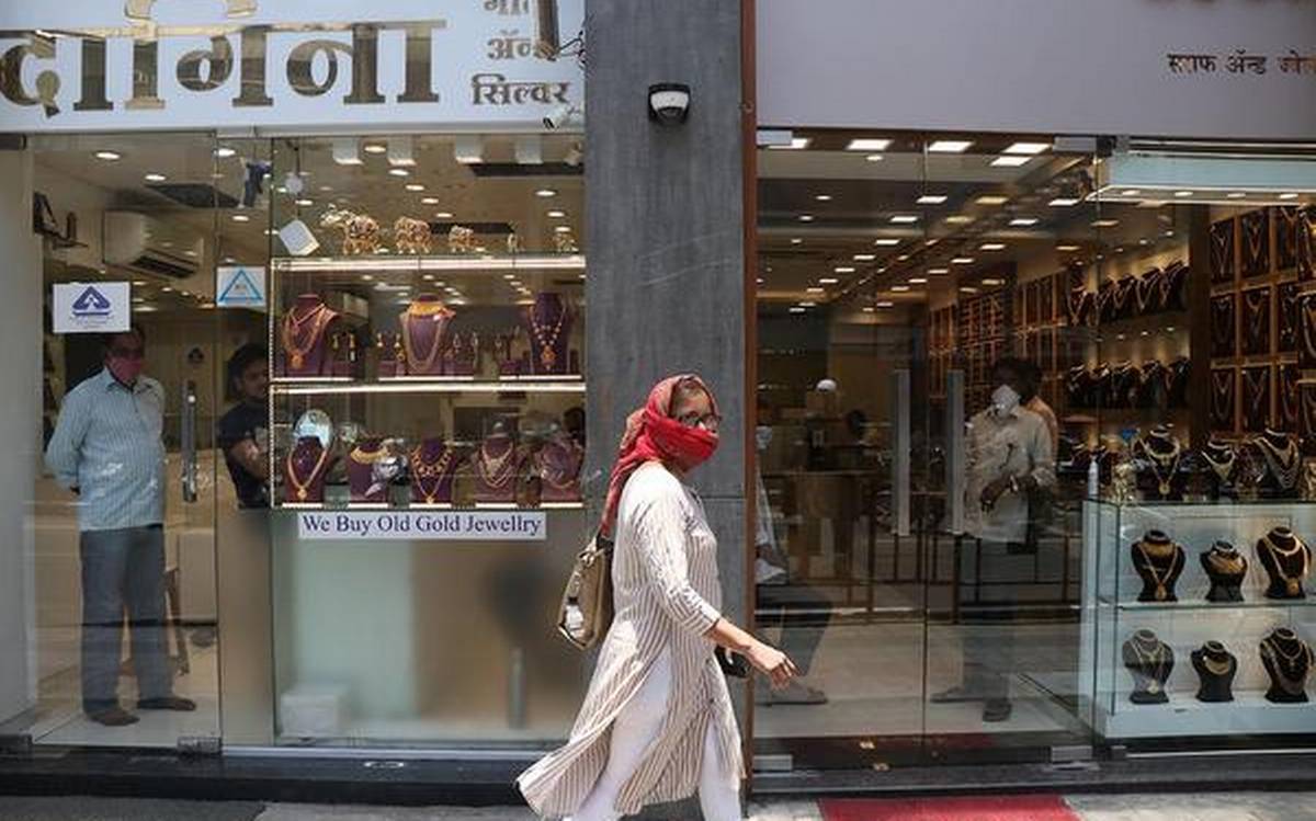 Image of a woman walking past Gold retailers wearing a mask